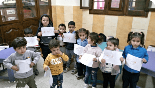 Some children in a classroom, each holding a piece of paper with their drawings. The children appear to be proudly displaying their artwork.